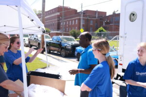 ShowerUp team members interact with guests, explaining how the mobile shower unit and hygiene products work.