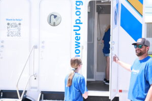 A staff person opens a door to a mobile shower unit at the Hospitality Hub in Memphis. ShowerUp, an organization based in Nashville, provides the hygiene unit.